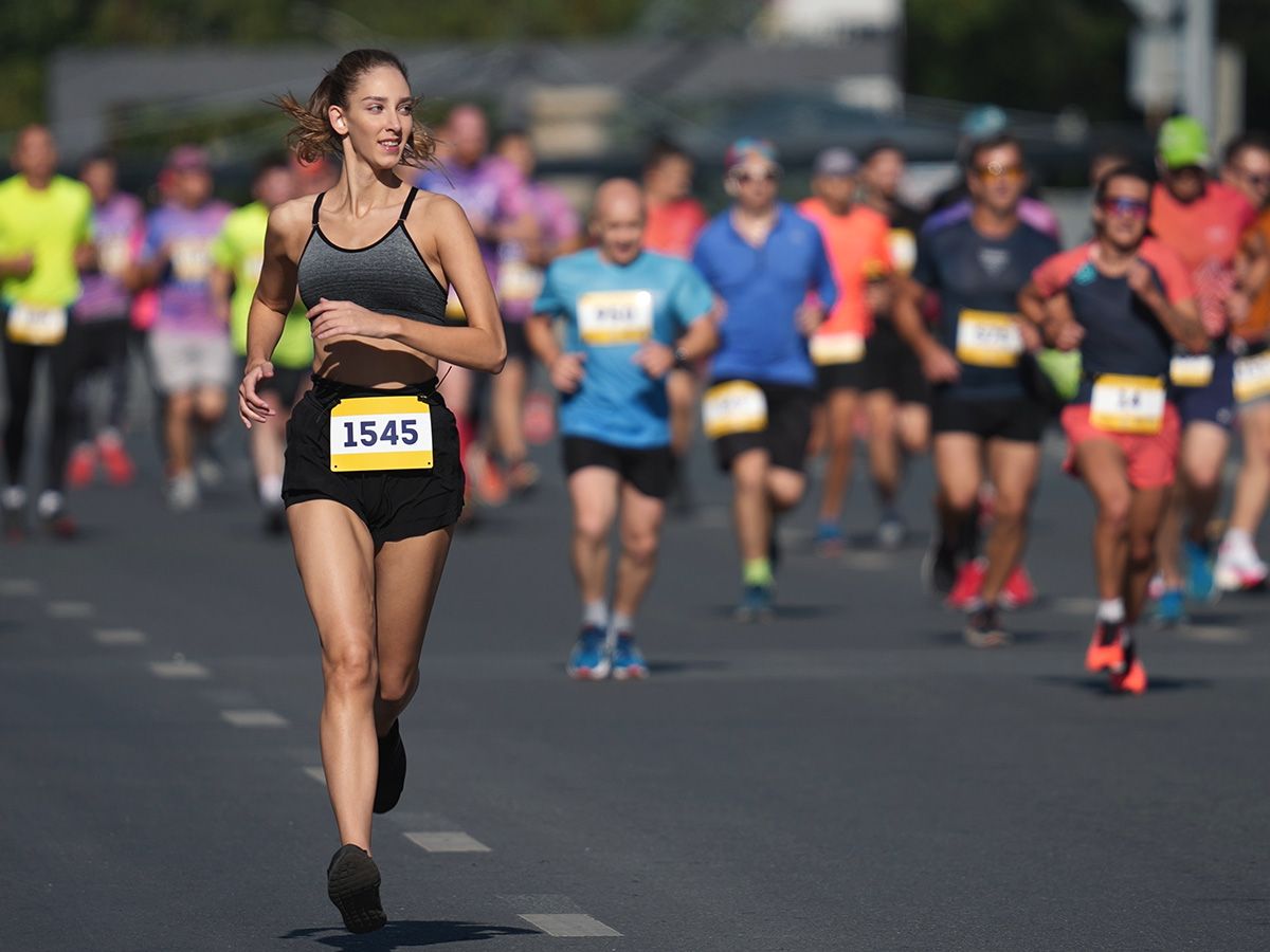 Kobieta prowadzi stawkę podczas maratonu ulicznego. - zdjęcie