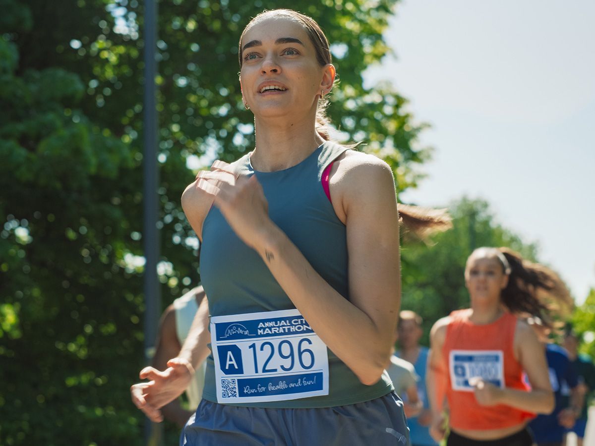 Zawodniczka biegnie w maratonie wśród innych uczestników. - zdjęcie
