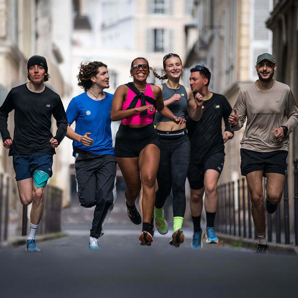 Grupa biegaczy w różnych strojach sportowych marki New Balance, biegnąca po ulicy w mieście. - tytułowa