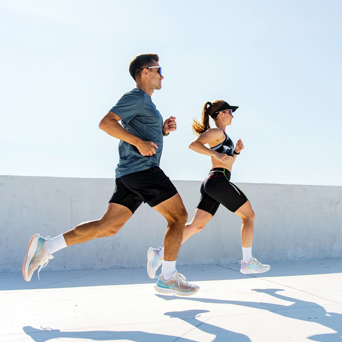 Dwoje biegaczy biegną w pełnym słońcu, ubrani w sportowe stroje. - tytułowa