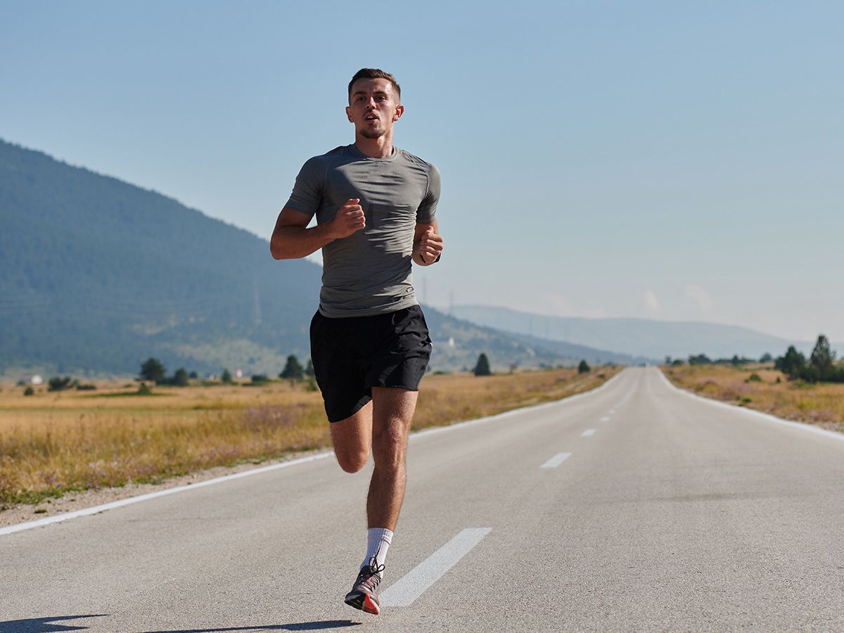 Mężczyzna biegnący po drodze w górach. - zdjęcie