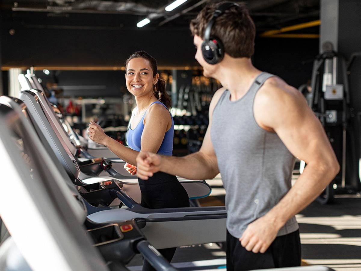 Kobieta i mężczyzna trenują na bieżniach na siłowni. - zdjęcie