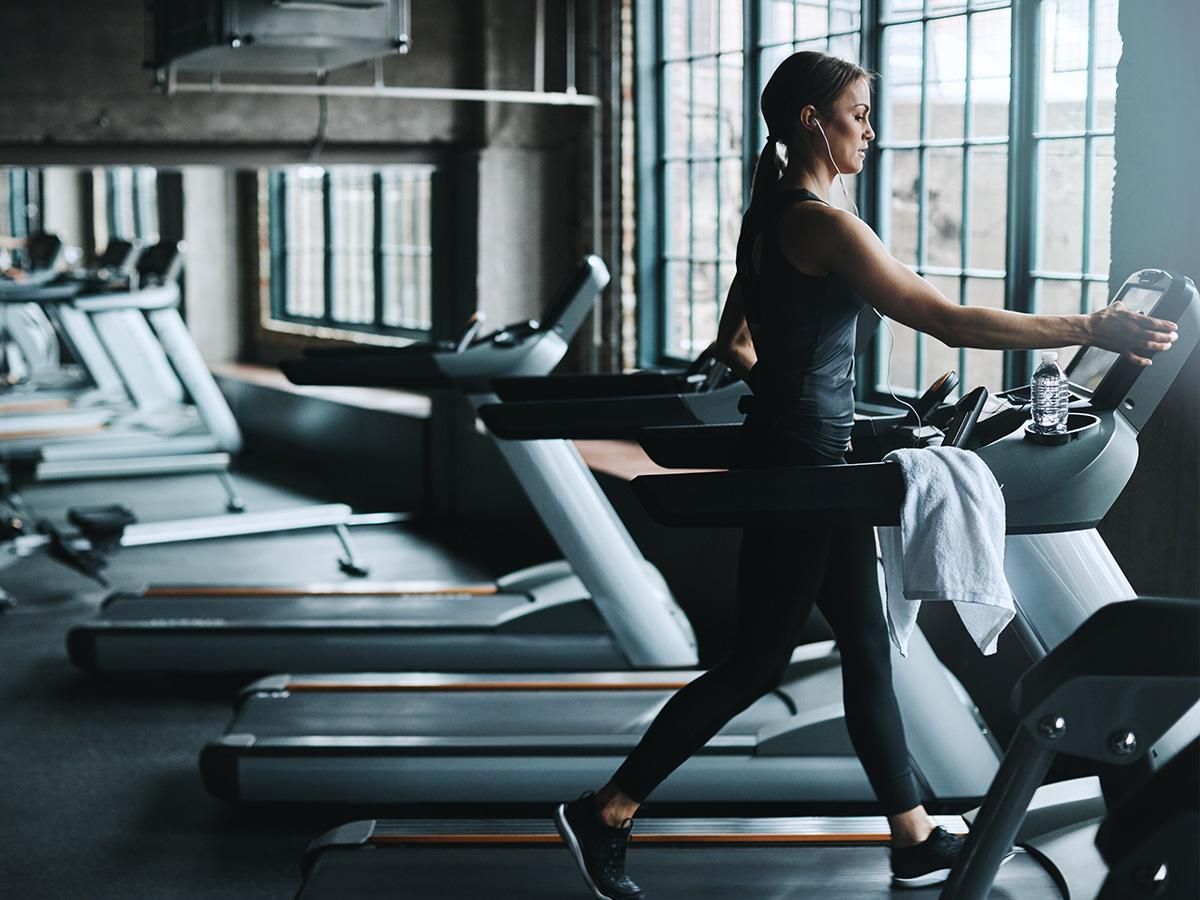 Kobieta idzie na bieżni w industrialnym wnętrzu siłowni. - zdjęcie