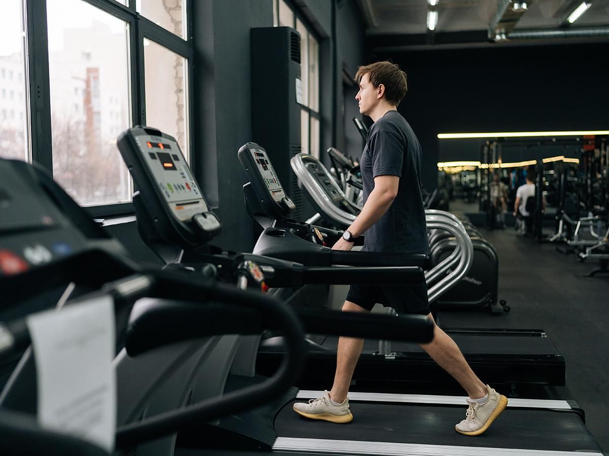 Mężczyzna ćwiczy na bieżni w nowoczesnej siłowni. - zdjęcie