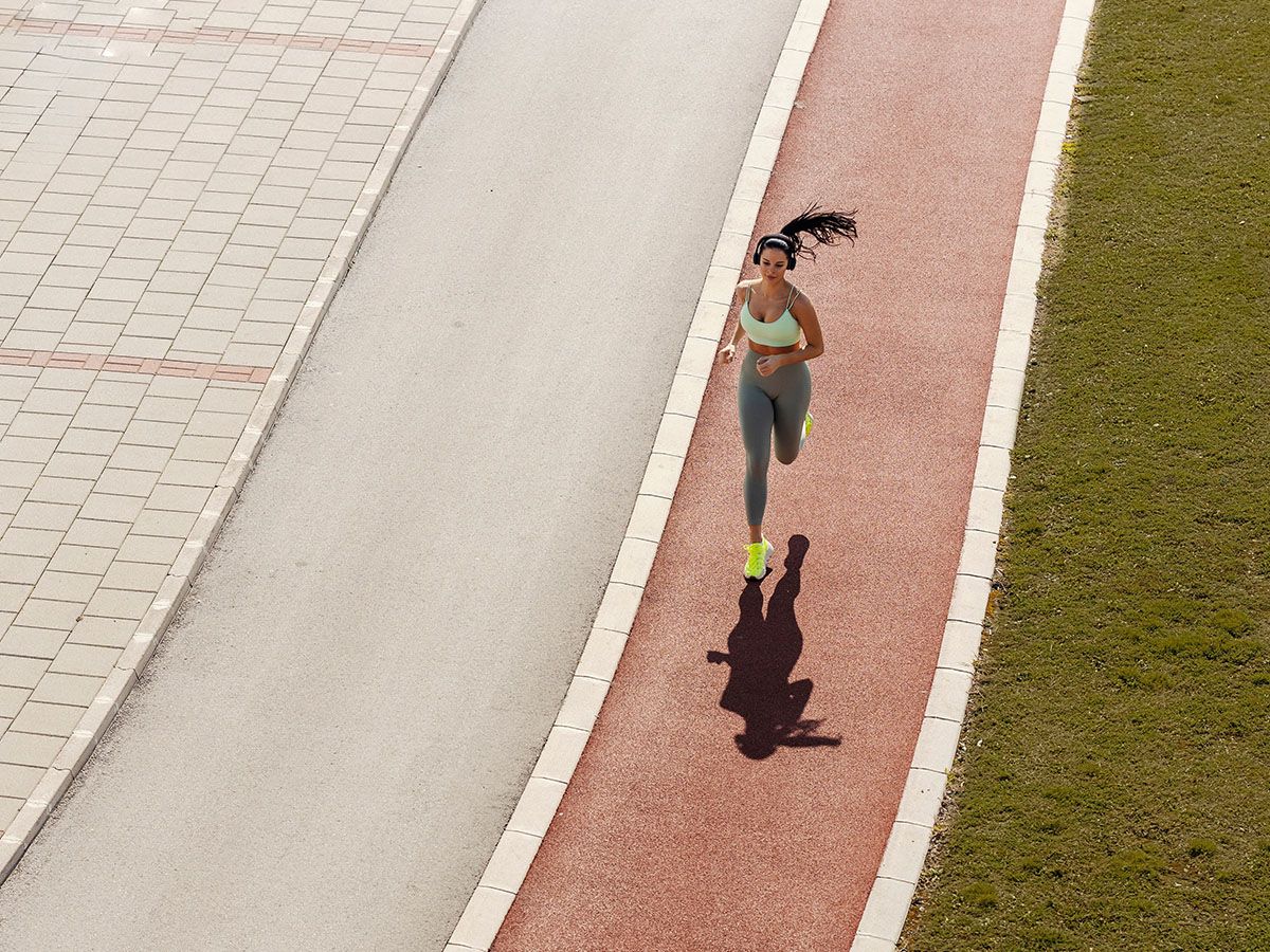 Kobieta biegnie po ścieżce sportowej. - zdjęcie