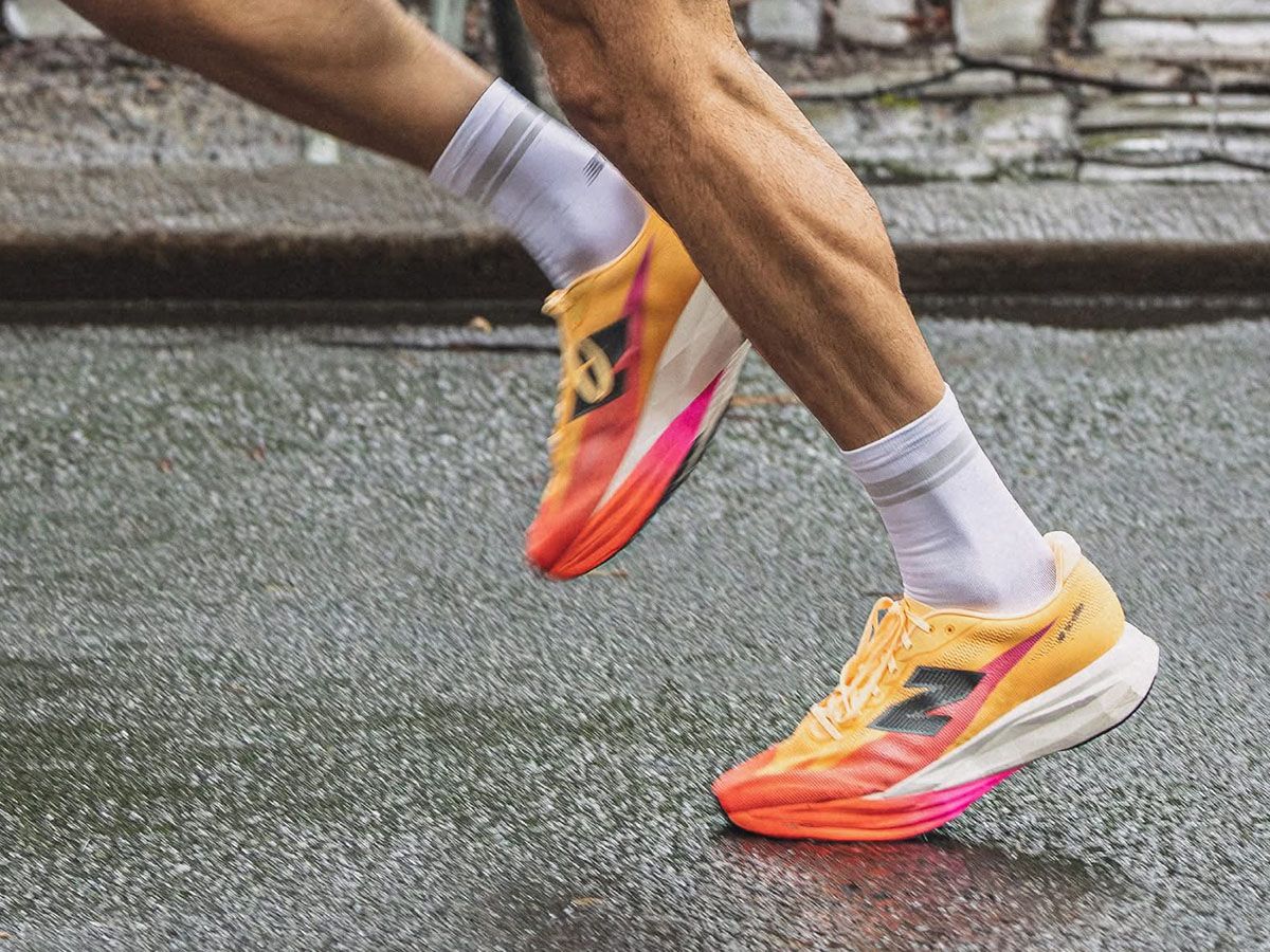 Zbliżenie na nogi biegacza w kolorowych butach New Balance do biegania na mokrej nawierzchni. - zdjęcie