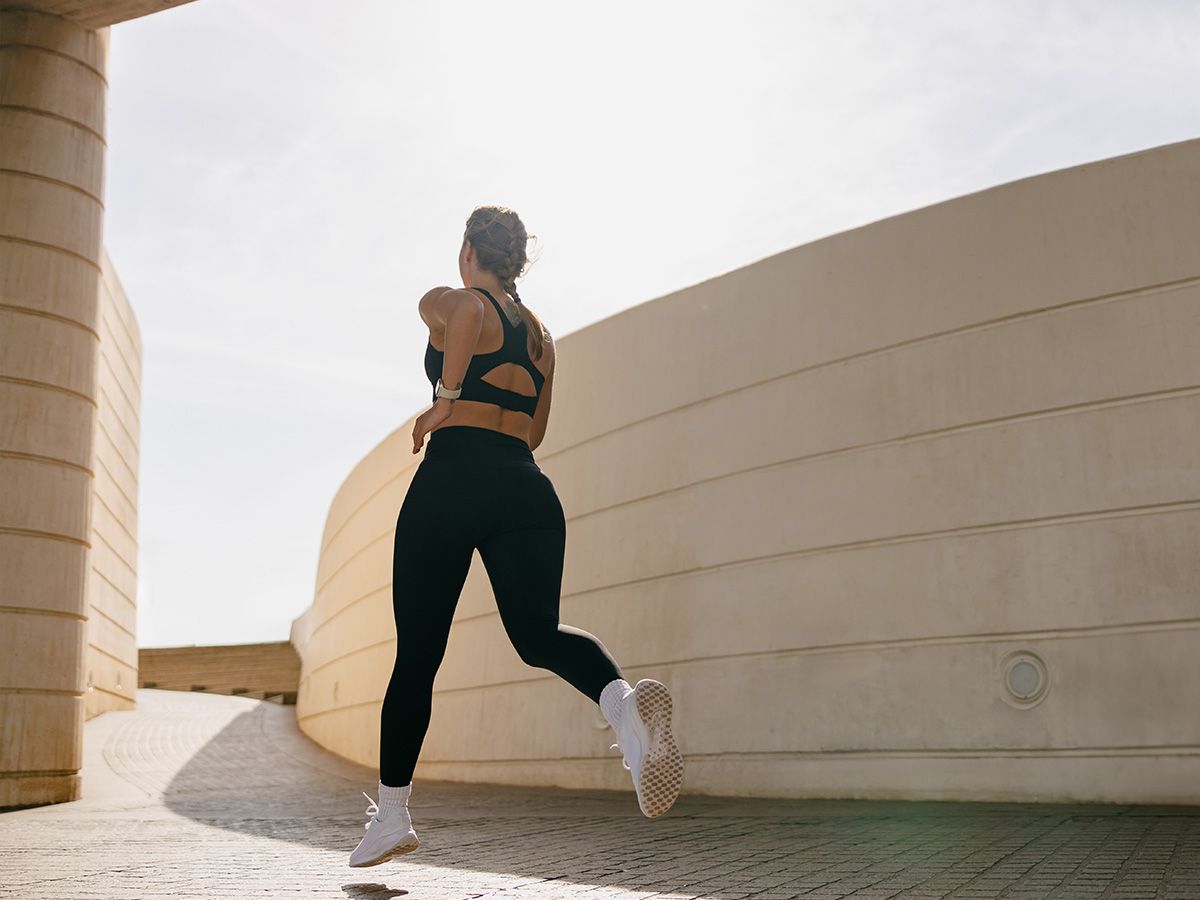 Biegnąca kobieta w czarnym stroju sportowy. - zdjęcie