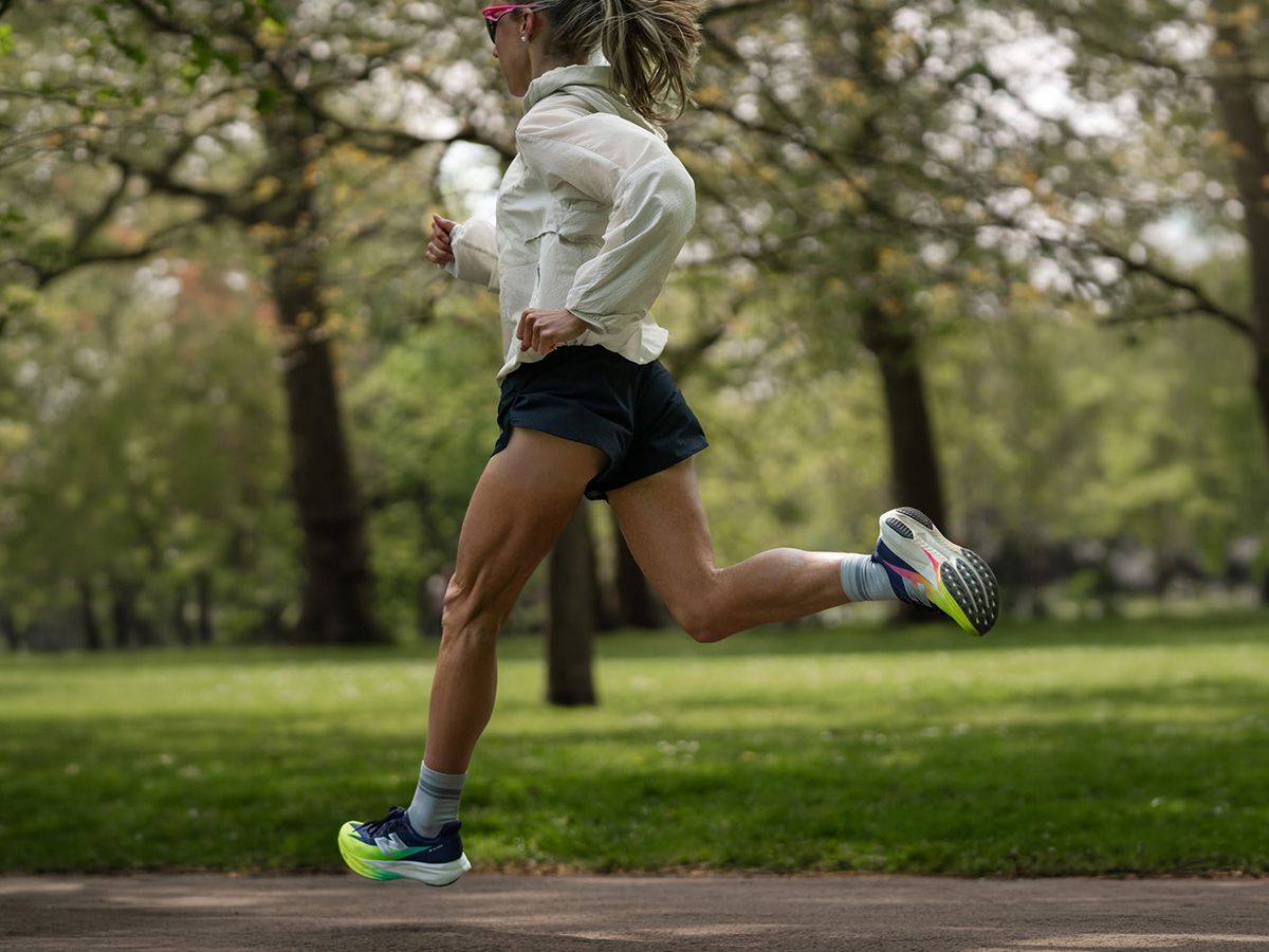 Biegnąca kobieta w parku w ubraniach i butach New Balance. - zdjęcie