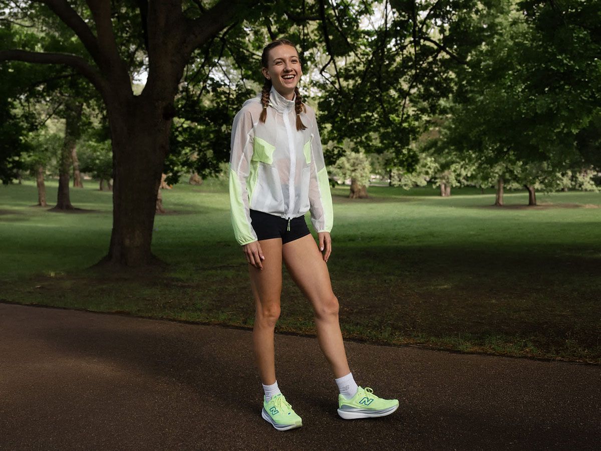 Uśmiechnięta kobieta w parku w ubraniach do biegania New Balance. - zdjęcie