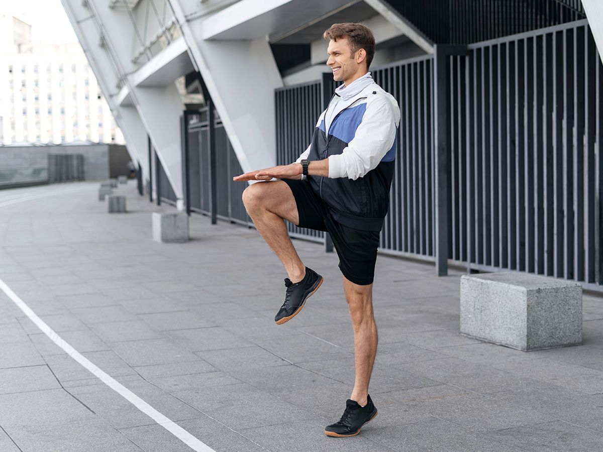 Mężczyzna wykonuje rozgrzewkę przed biegiem. - zdjęcie